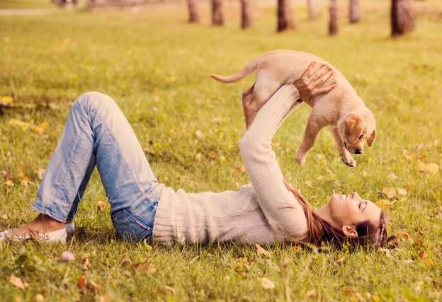 A woman playing with a puppy in happy mood
