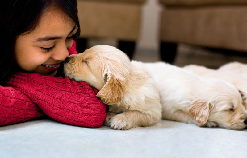 A lady kissing a puppy 